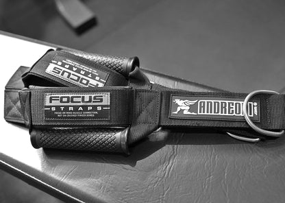 Black weightlifting cable machine handles with visible 'FOCUS STRAPS' and 'ANDREONI' branding on a gym bench