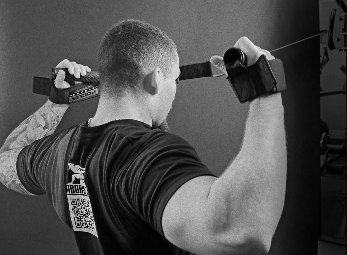 Person using a cable machine and Focus straps in a gym setting