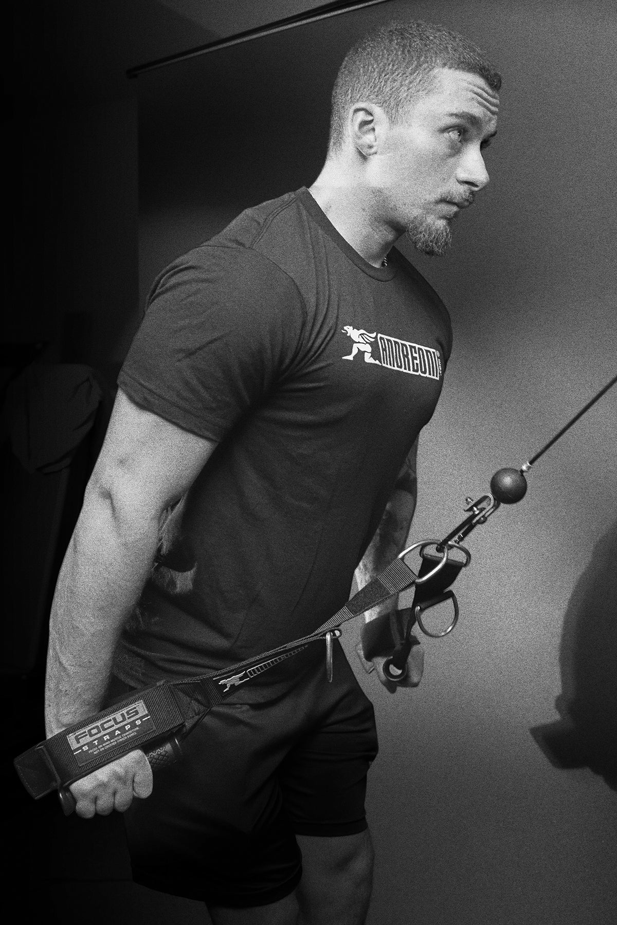 Black and white picture of weightlifter using Focus cable machine attachments to do pushdowns