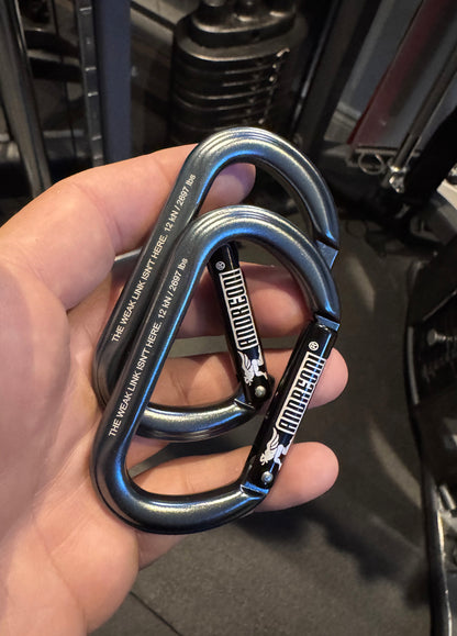 Andreoni aluminum gym carabiner in one hand next to a cable machine