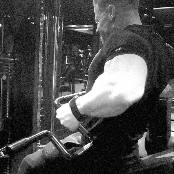 Black and white photo of man doing seated cable row on a cable machine